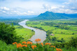 © Tetiana - Generative AI image of a vibrant spring landscape with a winding river, blooming wildflowers, and distant mountains