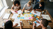 © Vika art - Top view of a creative diverse team brainstorming ideas with sticky notes on a wooden table.