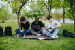 © Alexandr - Three caucasian teenage boys studying on park grass with laptop and books