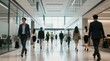 © jollier_ - Business professionals walk in a modern office building during the day near large windows