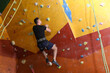 © New Africa - Athletic young man climbing wall in gym, back view. Space for text