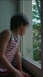 © Marco - Child sitting by window looking outside with thoughtful expression in quiet indoor moment observing nature and reflecting