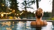© Bonsales - Woman relaxing in outdoor hot tub surrounded by trees and glowing string lights at sunset, enjoying peaceful evening