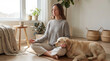 © alisluch - Copy space woman meditating beside golden retriever in calm living room with plants and warm sunlight for wellness relaxation