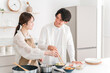 © buritora - A young Asian couple cooking in their home kitchen.