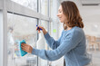 © Pixel-Shot - Young woman cleaning large window at home