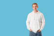 © Pixel-Shot - Young blonde man in white hoodie on blue background