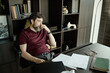© TrueFrame Collective - Middle aged Caucasian man sitting at office desk, thinking over pages of novel, suffering from creative block