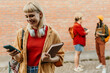 © La Famiglia - Student smiling while using phone on campus