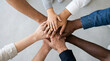 © HADI INCREDIBLE - Diverse group of people of different ages and ethnicities stacking their hands together in a circle to show unity and teamwork