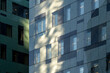 © yaqui_villegas - Soft sunlight crosses urban facade panels and windows, turning building architecture, glass and shadow into a calm exterior geometry study