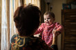 © Antonio Recena - Grandmother Holding Happy Baby Near Window in Cozy Home