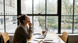 © SamTiara - Thoughtful Young Professional Contemplating Career Goals While Working Remotely at a Sunny Urban Cafe Office Desk