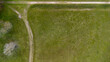 © zlatoust198323 - Top down aerial view of a green meadow with a dirt path intersection and a lonely bench. Minimalist rural landscape captured from above, showcasing texture, geometry, and peaceful countryside.