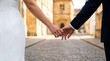 © Pedro Fiuza - Close-up of a bride and groom's hands with wedding rings about to touch while walking on a historic cobblestone street