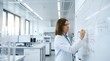 © Yuliia - Young Caucasian female scientist in white lab coat and safety glasses writing chemical formulas on whiteboard in modern laboratory.