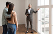 © Prostock-studio - Look Here. Professional House Agent Seller In Suit Showing New Apartment To Young Couple, Pointing At Beautiful View From Floor to Ceiling French Windows To Embracing Future Homeowners. Purchase