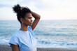 © SISMIZ - Woman with hand in hair looking out at the ocean at sunset