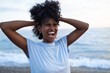 © SISMIZ - Joyful woman with curly hair laughing with eyes closed at the beach
