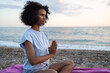 © SISMIZ - Woman meditating on a beach at sunset with hands in prayer pose