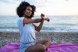 © SISMIZ - Woman stretching arms on beach blanket at sunrise with ocean waves