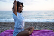 © SISMIZ - Woman stretching arms while meditating on a beach at sunset