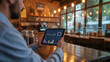 © desing25 - Restaurant manager utilizing advanced software to monitor real time sales data on portable pad.