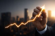 © Pixel Studio - Business Growth Chart: A close-up of a hand drawing an upward trending financial graph on a city skyline backdrop, symbolizing economic progress and investment success.