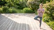© Artem Zatsepilin - cute caucasian little girl practicing yoga tree pose on wooden terrace outdoors. kids mindfulness, healthy active lifestyle in nature. copyspace, banner, website header.