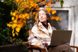 © Соня Монштейн - A young woman is resting her eyes after working on a laptop on a cozy autumn terrace in the daylight. The front view portrait.