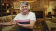 © Krakenimages.com - Man wearing white headphones smiling and gesturing with open hand in a cozy living room inside a building; comfort relaxation leisure.