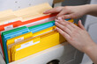 © New Africa - Tax. Woman looking through office folders in drawer of cabinet indoors, closeup