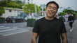 © Krakenimages.com - Man wearing black t shirt smiles and sticks tongue out while standing on urban street lined with blurred cars; playful joy.
