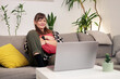 © MexChriss - Woman relaxing on couch watching laptop computer