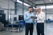 © sukarman - Industrial Engineers Discussing Production Data on Digital Tablet in Modern Factory