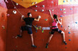 © New Africa - Athletic man and woman climbing wall in gym, back view