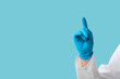 © Pixel-Shot - Doctor's hand pointing at something on blue background, closeup