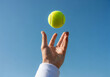 © MstMorjina - Person throwing a yellow tennis ball into the clear blue sky