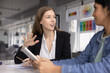 © fizkes - Young businesswoman in formal attire lead conversation with female colleague holding digital tablet at briefing in boardroom in modern office. Brainstorm, ideas exchange during creative team meeting