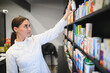 © Serhii - Pharmacist reaching for medicine on pharmacy shelf