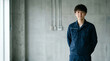 © Y Creative Stock - 手を後ろで組んで立つ設備管理・電気工事士の男性、求人・採用イメージ