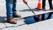 © NaesyaStudio - Road maintenance worker applying asphalt sealant to cracked pavement with a roller