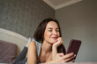 © Westend61 - Smiling woman using a smartphone while relaxing on a bed at home