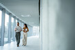 © Migma_Agency - Business coworkers walking in modern office hallway discussing work