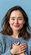 © spyrakot - Woman with hand on chest expressing calm and gratitude on blue background