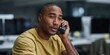 © Andrii Zastrozhnov - Man listening intently on phone in busy office setting