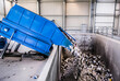 © Lenz Studio - Sustainable waste management facility in action, with an industrial compactor efficiently emptying discarded materials for modern recycling success