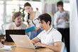 © JackF - Young office worker works on laptop in a modern open-plan office