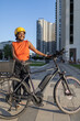 © aerogondo - Young African Woman stands beside her electric bike in the city