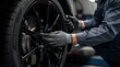 © PengAI - A mechanic wearing gloves uses a wrench to tighten the lug nuts on a black car wheel in an auto repair shop.